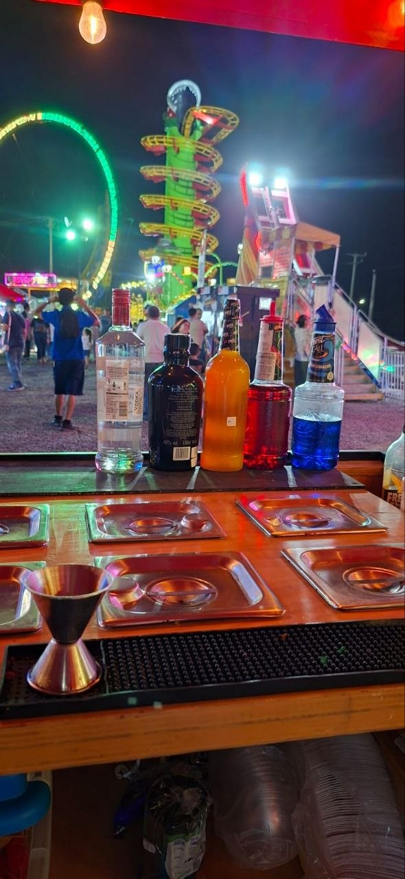 Botellas y utensilios de coctelería listos en la barra durante una feria nocturna